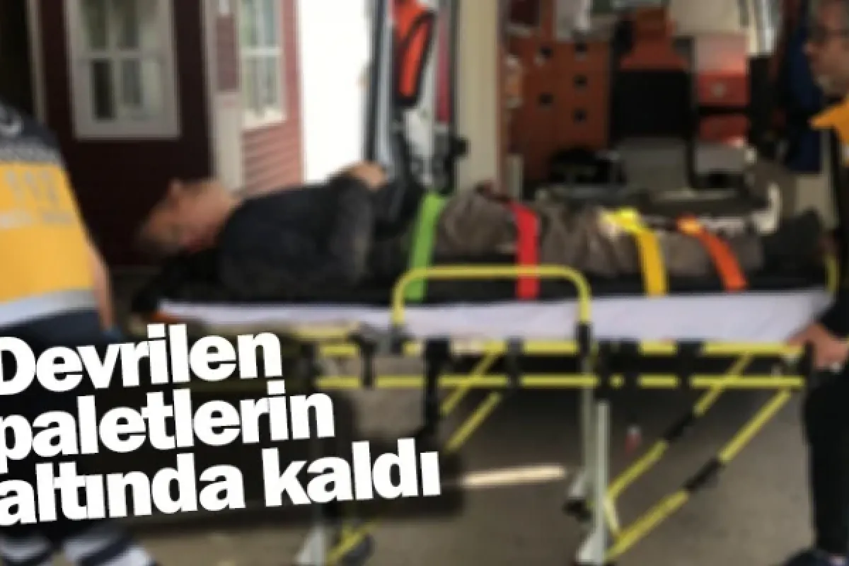Devrilen paletlerin altında kaldı